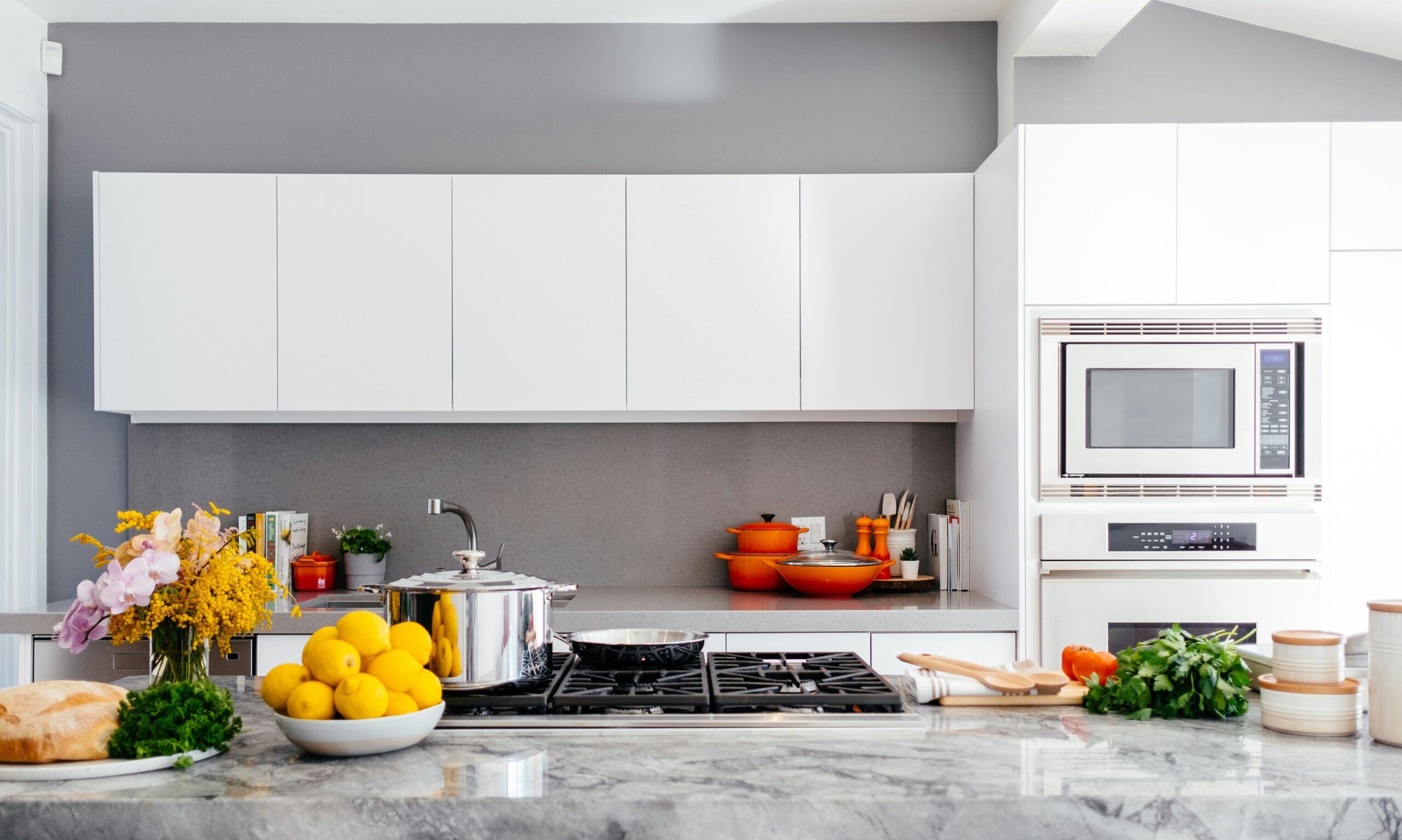 photo-1556911220-bff31c812dba a kitchen with white cabinets and a bowl of lemons